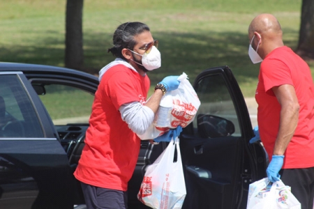 A volunteer unloads food from a car during Saturday’s “Share Your Blessings” food drive at the Ismaili Jamatkhana and Center. (P